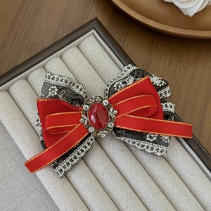 Retro bow hair clip with red satin, lace, and red gemstone in vintage gold setting