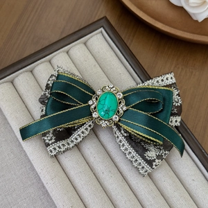 Detail of vintage dark green satin bow hair clip with lace and marble gemstone