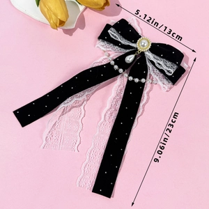 Detail showing vintage black velvet bow hair clip with lace edges and pearl pendant