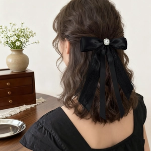 Elegant black lace and satin bow hair clip with rhinestone worn by a woman