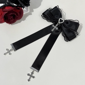 Détail du nœud gothique en dentelle avec pendentifs cœur et croix sur surface grise