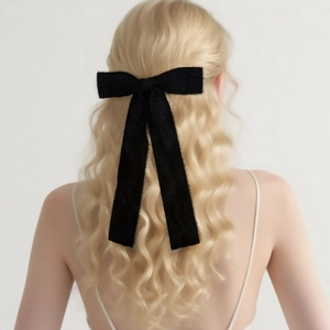 Elegant black tweed bow hair clip with long ribbons on blonde wavy hair