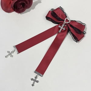 Détail du nœud gothique rouge foncé avec pendentif cœur et breloques en croix
