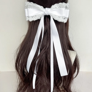 Gros plan d'une pince à cheveux en dentelle blanche avec de longs rubans élégants
