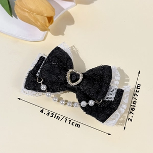 Détail d'une pince à cheveux Lolita en dentelle noire avec cœur en strass et pendentifs