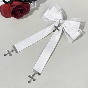 Détail d'un nœud en satin blanc avec bordure en dentelle et pendentifs croix argentées