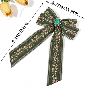 Detailed view of bohemian green bow hair clip with floral embroidery and gemstone