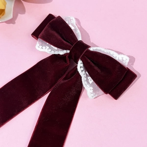 Detail of burgundy velvet hair clip with white lace trim and long flowing ribbons