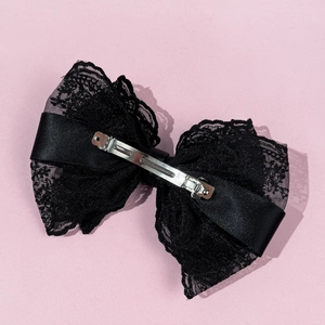 Elegant large black lace bow hair clip with metal spring clasp on pink background