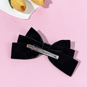 Elegant black velvet layered bow hair clip with silver metal crocodile clip on pink background