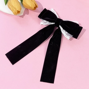 Detailed macro view of black velvet hair clip with white lace trim and long elegant streamers