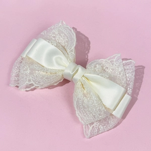 Elegant oversized cream lace bow hair clip with satin ribbon for women on pink background
