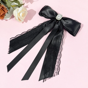 Close-up of elegant black satin lace bow hair clip with crystal rhinestone center