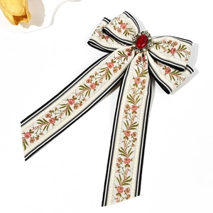 Detail of floral ribbon bow hair clip with central red gemstone and crystal setting