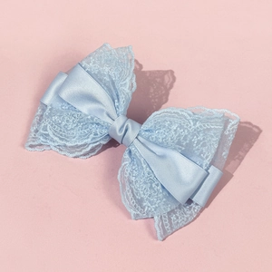 Macro detail of a multi-layer light blue lace and satin bow hair clip with fine texture
