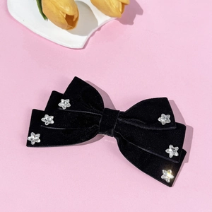 Detail of black velvet bow hair clip with sparkling silver star rhinestones