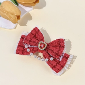 Détail d'un nœud à cheveux en tweed rouge avec dentelle blanche, gemme cœur et perles