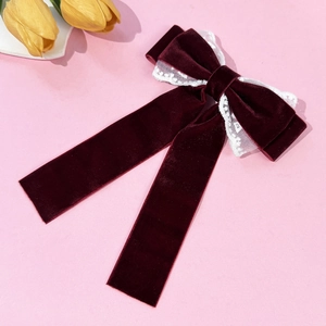Detail of burgundy velvet bow hair clip with white lace trim and long ribbons