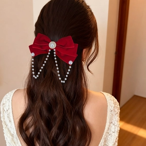 Elegant red velvet bow hair clip with pearl chain tassels shown on model hair