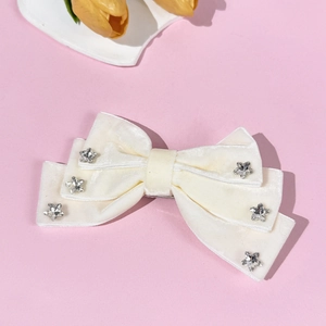 Detail of white velvet bow hair clip with sparkling star rhinestones and metal spring clip
