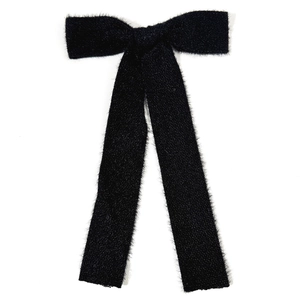 Detail of elegant black fuzzy ribbon bow hair clip with soft wool-like texture