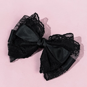 Close-up of elegant black lace bow hair clip with layered satin and floral patterns