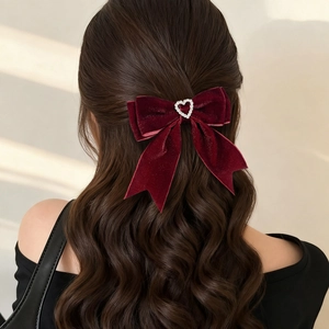Close-up of velvet wine red bow hair clip with a sparkling rhinestone heart on hair