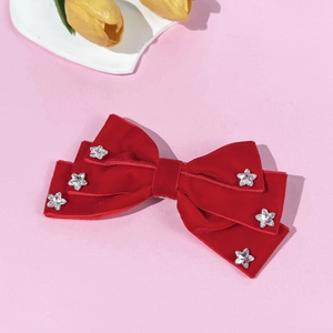 Elegant red velvet bow hair clip with crystal star decorations on pink background