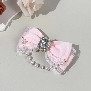Détail d'un nœud en satin rose avec dentelle et cristal au centre de la barrette