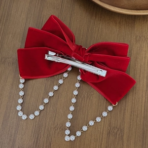 Elegant red velvet bow hair clip with luxury pearl tassels on a rustic wood background