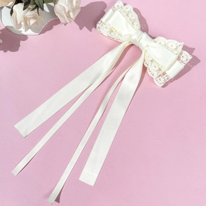 Pince à cheveux élégante avec nœud en dentelle crème et longs rubans sur fond lilas