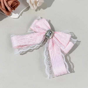 Détail d'une pince à cheveux nœud Lolita rose avec dentelle blanche et grand cristal