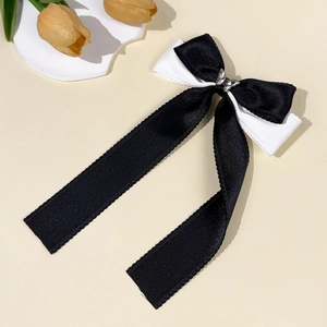 Detailansicht einer schwarz-weißen Schleifen-Haarspange mit silbernem Schmetterling