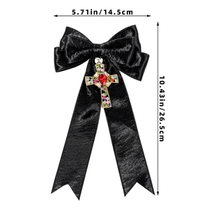 Détail du nœud en satin noir avec pendentif croix en cristal coloré et pierre rouge