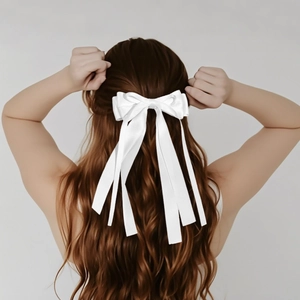Elegant white satin oversized bow hair clip with long ribbons on wavy brown hair