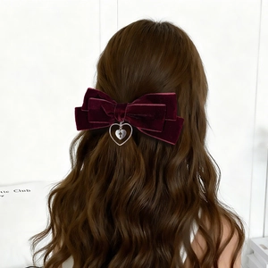 Détail du nœud papillon en velours bordeaux avec pendentif cœur croix sur cheveux
