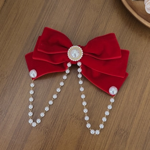 Detailed view of red velvet bow hair clip with faux pearl fringe and vintage tassel strands