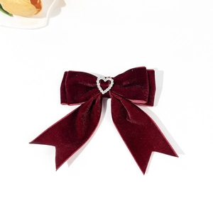 Macro detail of wine red velvet hair clip featuring a sparkling heart rhinestone buckle