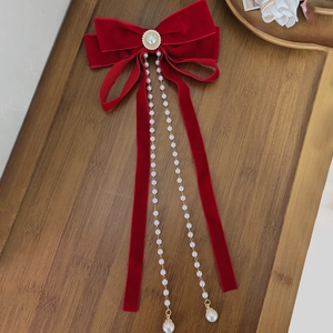 Detail of red velvet bow hair clip with luxury pearl tassels and rhinestone center