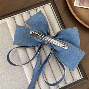 Blue denim bow hair clip with brown stitching and silver metal crocodile grip