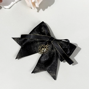 Detail of gothic black glitter bow hair clip with gold trim and hollow heart cross pendant