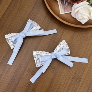 Details von süßen blauen Schleifen-Haarclips mit weißer Spitze auf Vintage-Holzgrund