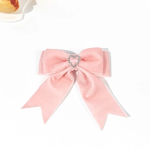Detailed close-up of pink velvet bow hair clip with a sparkling rhinestone heart