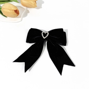 Detail of velvet bow hair clip with a silver heart rhinestone and long ribbons