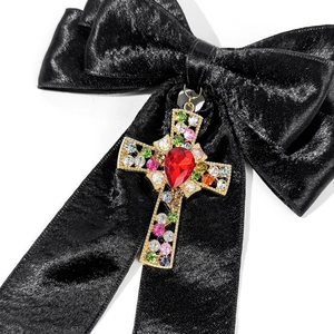 Vue détaillée du nœud en satin noir avec pendentif croix orné de strass colorés