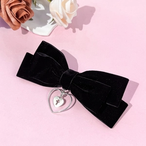 Détail du nœud en velours noir avec pendentif cœur croix vintage sur fond rose poudré