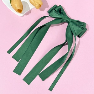 Close-up of elegant dark green satin ribbon bow hair clip with tiered pleats