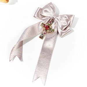 Vue détaillée du nœud en satin violet clair avec un pendentif croix en strass