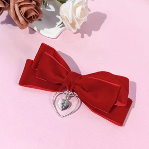 Détail de la pince à cheveux noeud en velours rouge avec pendentif coeur et croix argenté