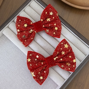 Dettaglio di fiocchi per capelli in velluto rosso con stelle dorate natalizie